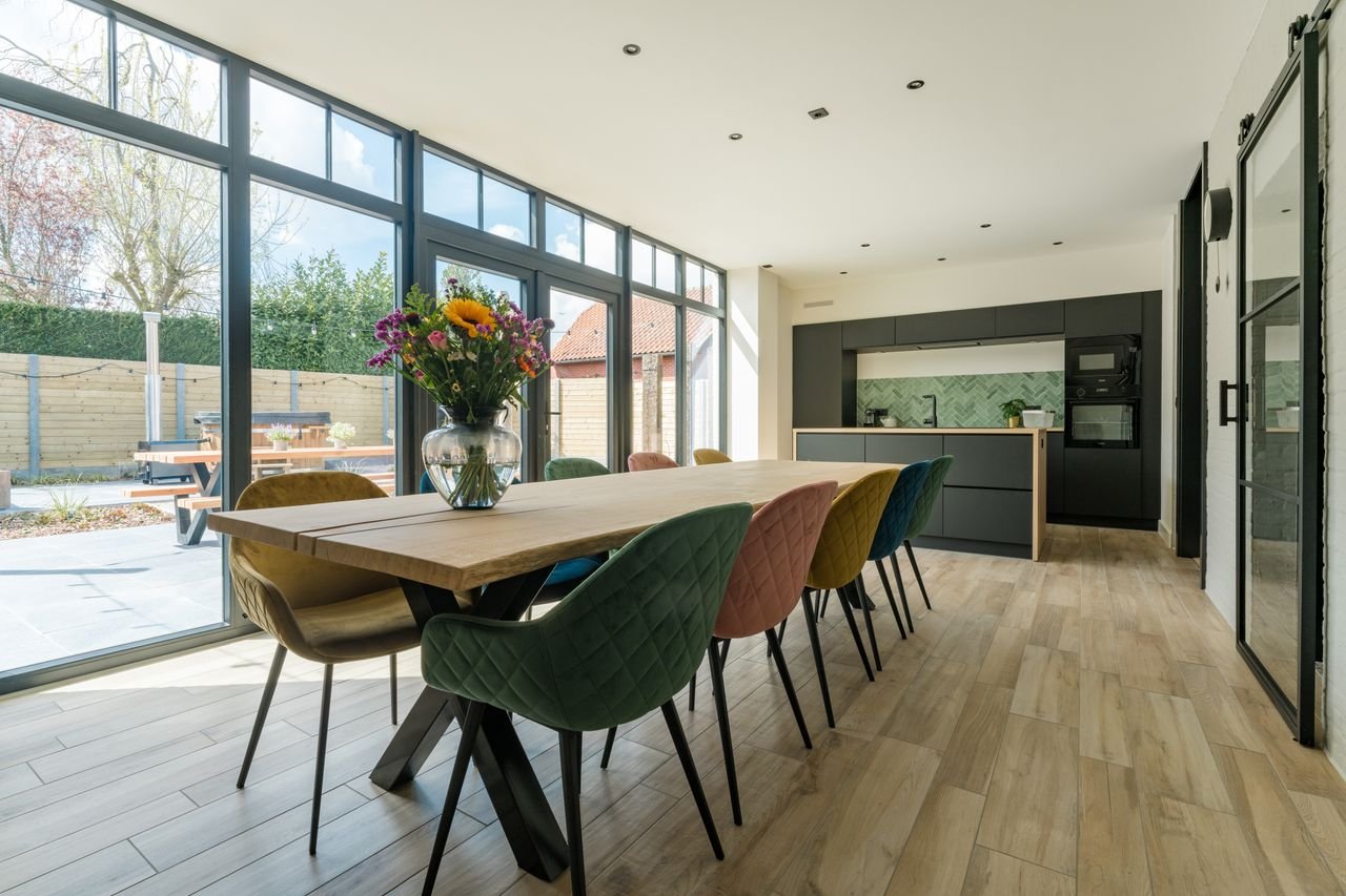 Bright dining room with colorful chairs and modern kitchen, perfect for design inspiration.
