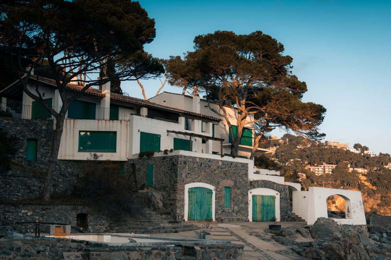 Charming coastal houses with green shutters in Catalonia, Spain during sunset.